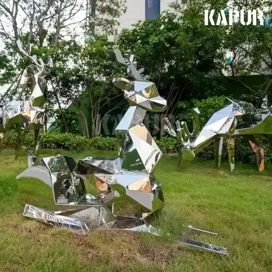 Polished stainless steel geometric deer sculpture standing in a modern garden setting