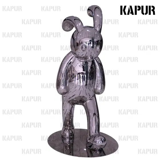 Polished stainless steel rabbit animal sculpture standing in a garden setting with greenery around it