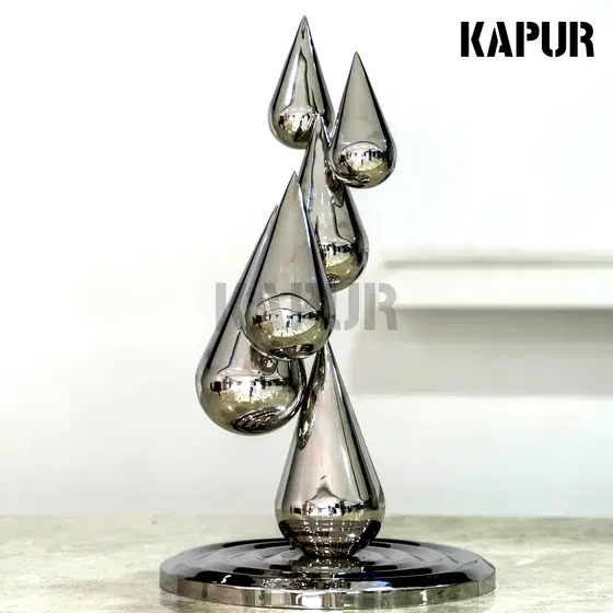 Polished stainless steel water drop ripple abstract sculpture standing in an outdoor garden setting