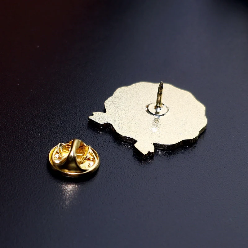 Multiple 25mm green lapel pins laid out on a surface, showing consistent colour and size