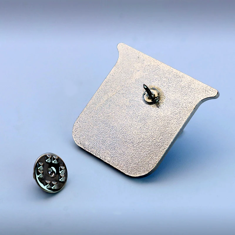 Lapel pin worn on a jacket lapel, showing the blue fish design and polished silver finish
