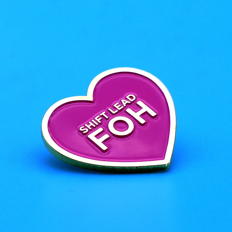 Close-up of a heart-shaped enamel pin showing soft enamel fill and metal edges