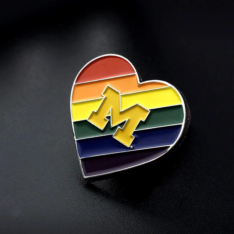 Close-up of the M logo and soft enamel fill on a heart-shaped lapel pin