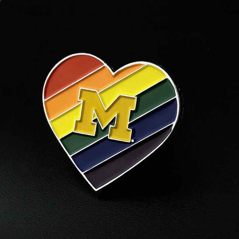 Heart-shaped lapel pin with white M logo and red enamel on a polished silver finish