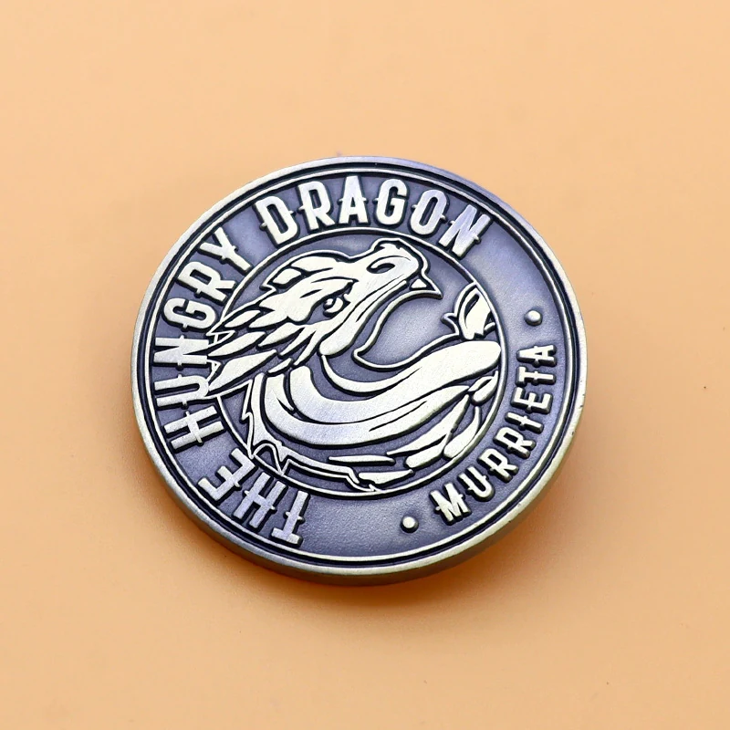 Group of custom antique brass dragon head challenge coins with different orientations and finishes
