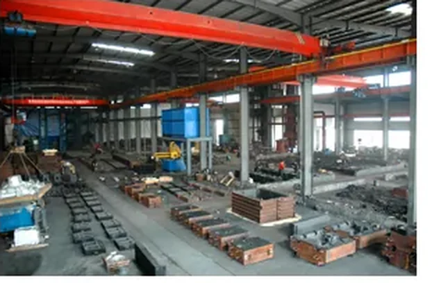 Machining hall with overhead crane and pump bodies staged along the aisle