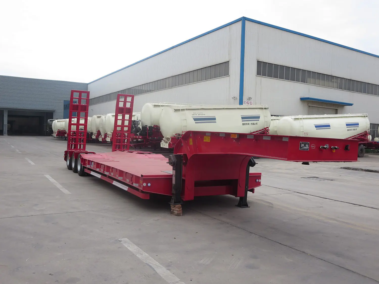 Row of SINOHENG low bed semi trailers and powder tankers lined up outside the Liangshan factory