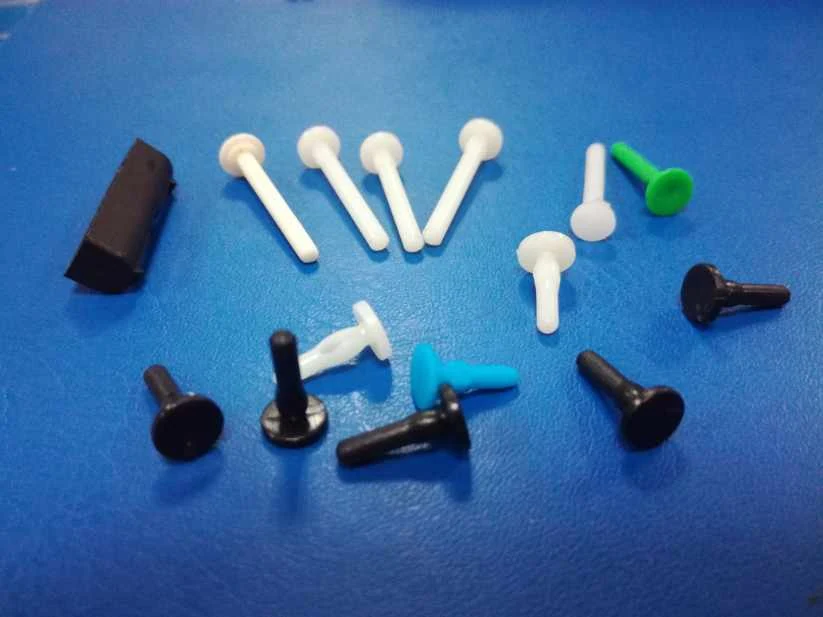 Plastic end pins in blue, white, black, and red colors laid out on a white surface