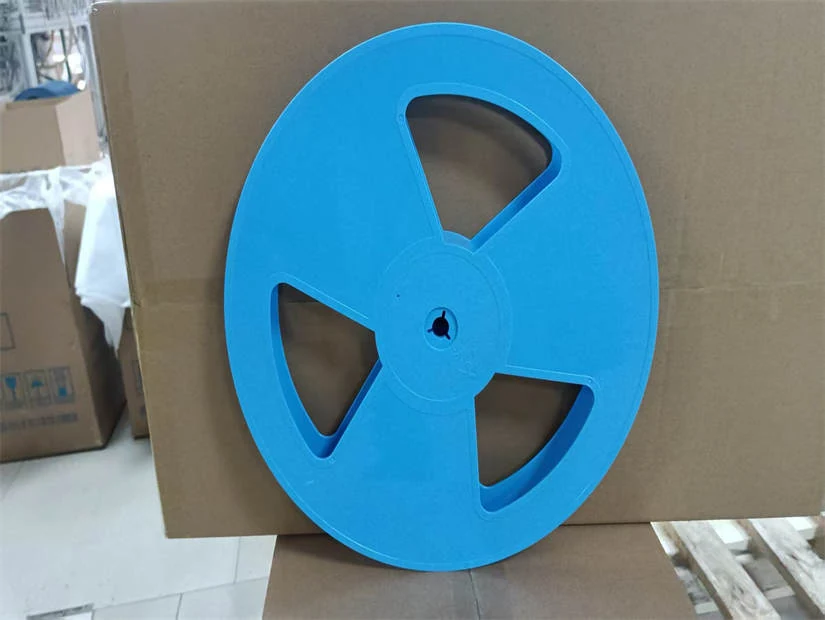 Large blue plastic reel with three spoke cutouts leaning against a cardboard box