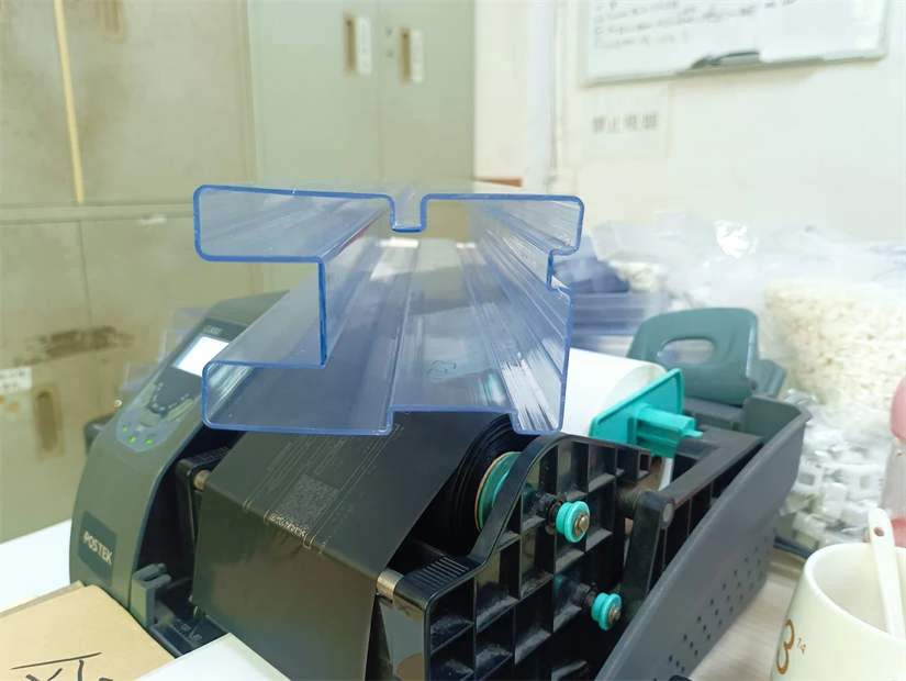 Clear plastic U-channel profile resting on a black machine
