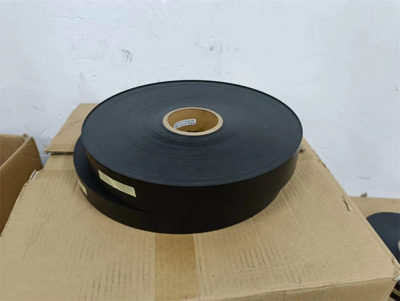 Large roll of black plastic strapping sitting on stacked cardboard boxes