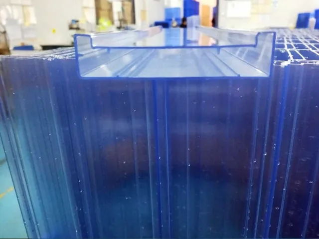 Stack of blue multiwall polycarbonate sheets with a U-shaped profile resting on top