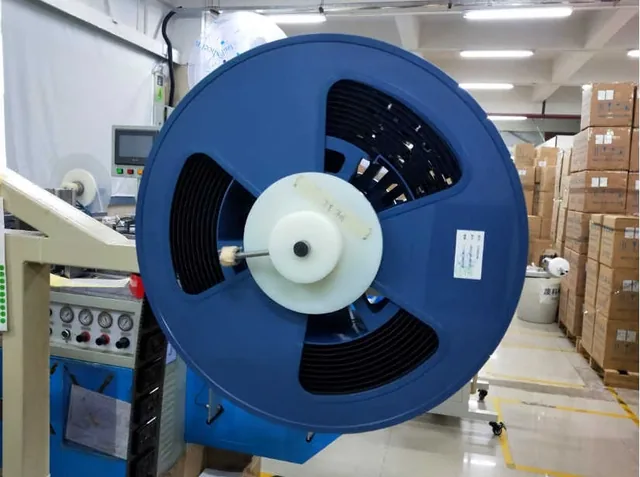 A large blue industrial reel mounted on a machine inside