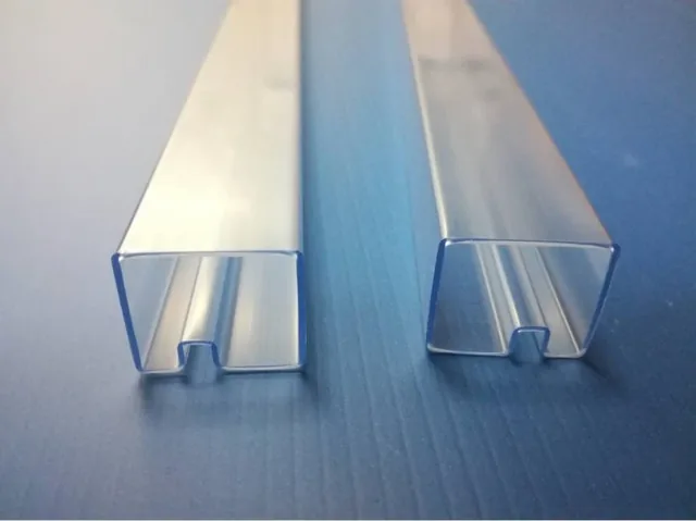 Two transparent slotted plastic extrusion profiles shown end-on
