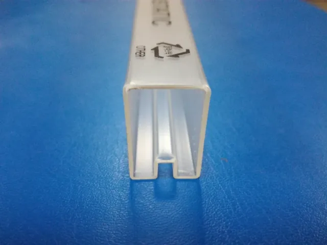Close-up of a white plastic extrusion profile with a channel and a bottom notch, resting