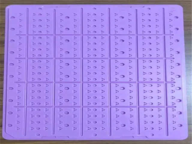 Purple perforated plastic grid tray with square compartments photographed at an angle