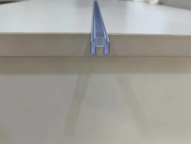 Translucent blue H-channel plastic edge trim profile being fitted onto the edge