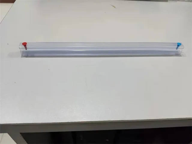Long clear plastic rail strip with red and blue end caps lying