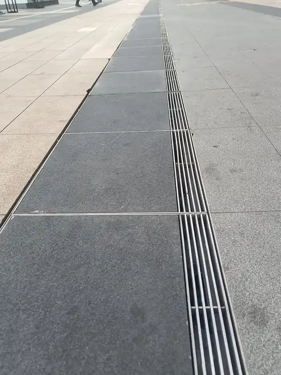 Heel guard grating slots set flush into stone paving outside a building entrance