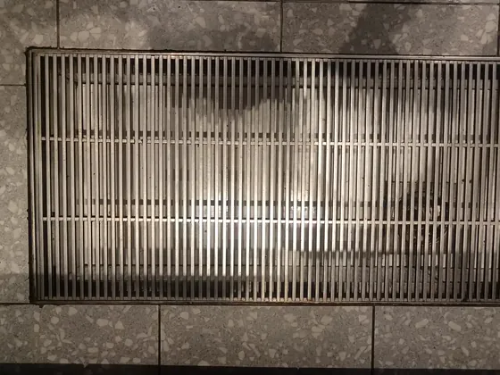 A stainless steel grating panel standing against a wall at the plant