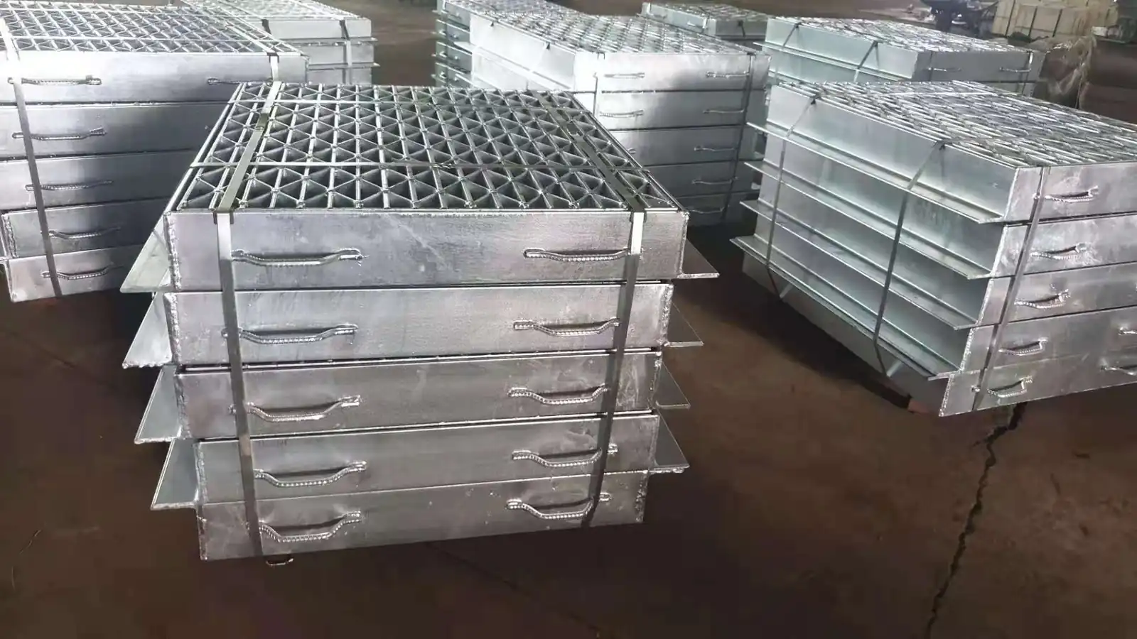 Hot-dip galvanized concrete cover grating panels with welded hooks stacked at the plant