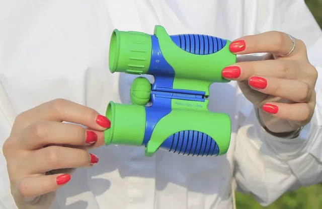 Hands holding green and blue binoculars