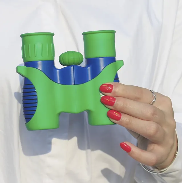 Hand holding green and blue toy binoculars
