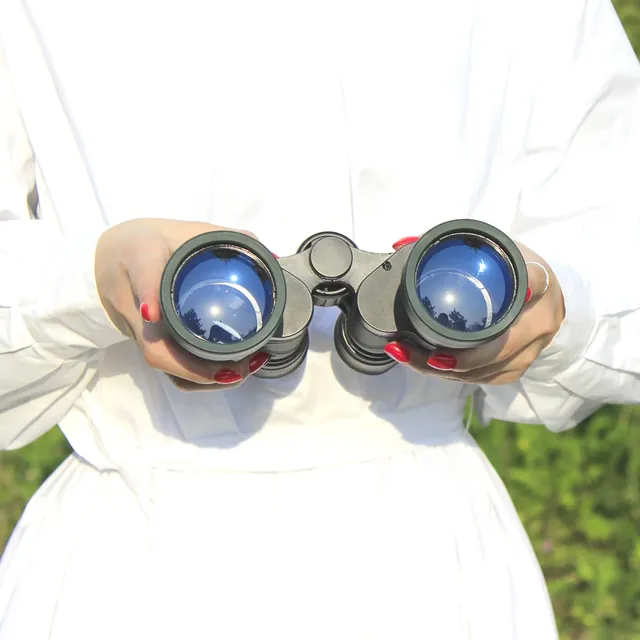 Hands holding a pair of black binoculars with blue reflective lenses