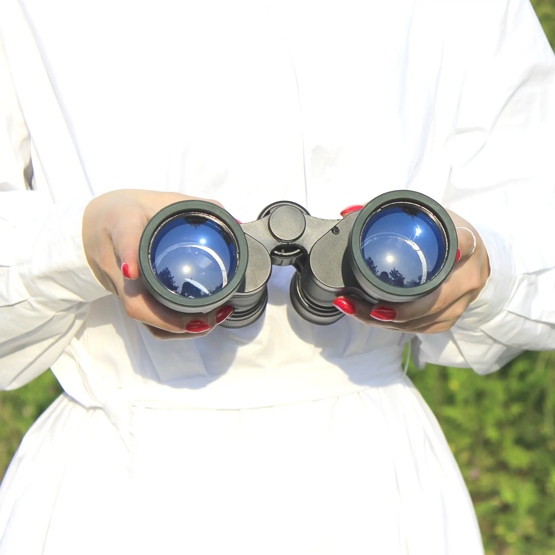 Hands holding a pair of black binoculars with blue reflective lenses