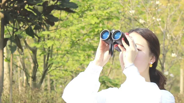 Shinyzen roof prism binoculars being used outdoors in a park