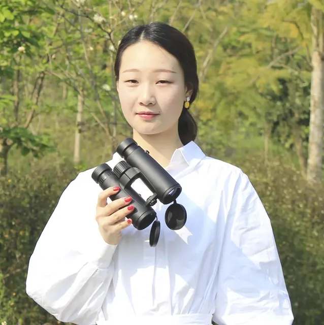 Woman holding black binoculars outdoors