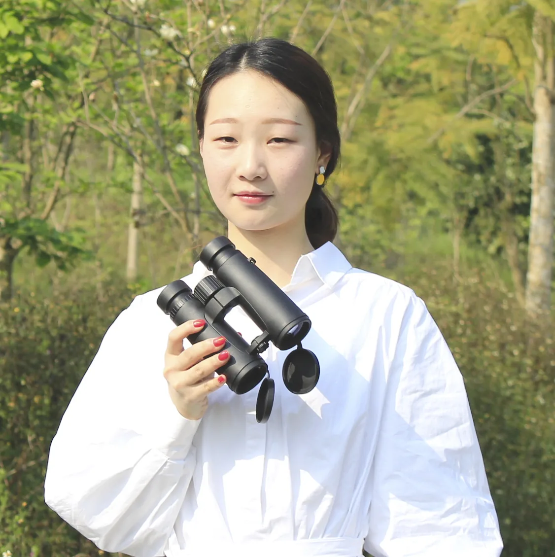 Woman holding black binoculars outdoors