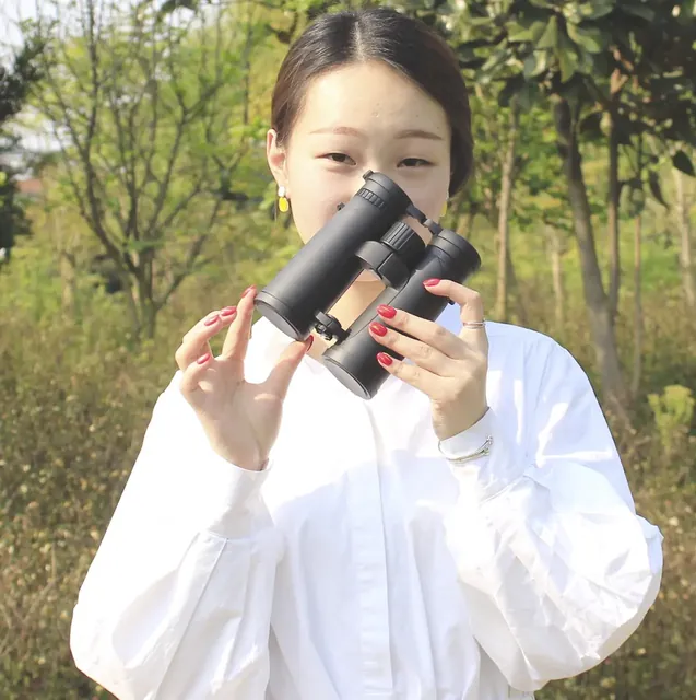 A woman holding a pair of black binoculars outdoors