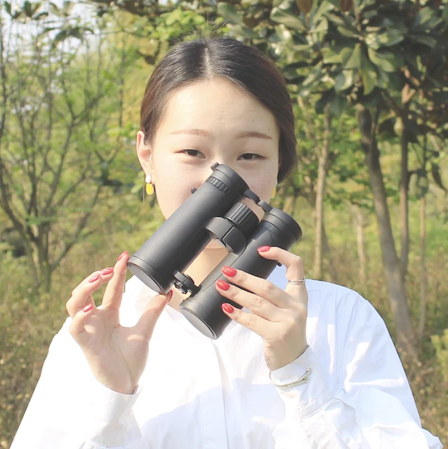 Woman holding black binoculars outdoors