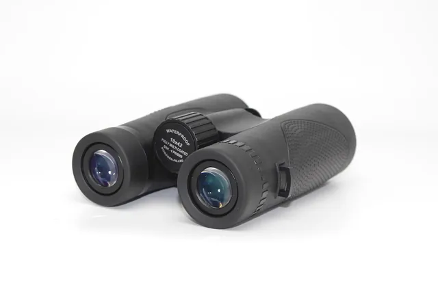 A pair of black binoculars resting on a white background