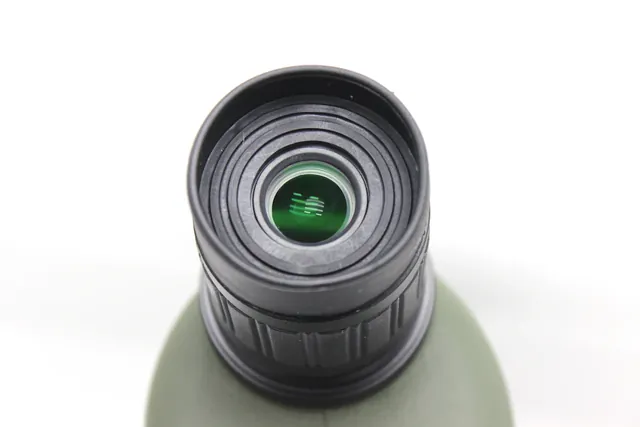 Close-up view of a monocular lens with green coating on a white background