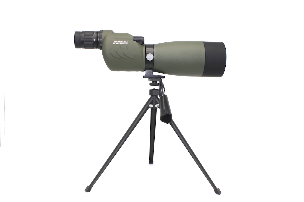 Green spotting scope mounted on a black tripod against a white background