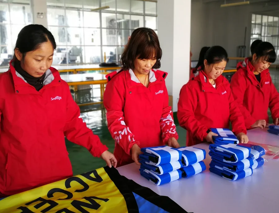 Packing line. Finished flags are folded, bagged and counted against the order before the c