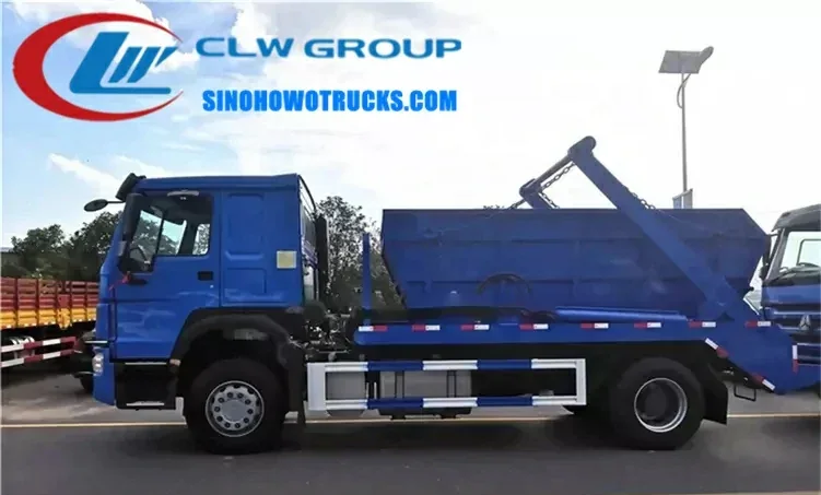 Sinotruk HOWO 12m3 skip loader truck with swing arm lifting a sealed skip bin at a waste collection site