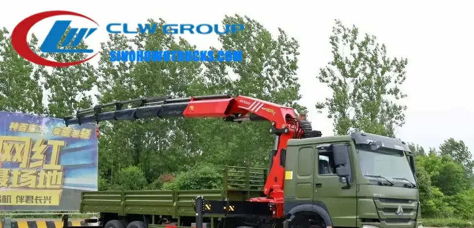 Sinotruk HOWO 18 ton knuckle boom crane in action at a construction site with boom extended and load suspended