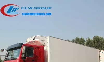 12 wheel Sinotruk HOWO 40ft chiller van truck in white with rear door open and PVC strip curtain visible