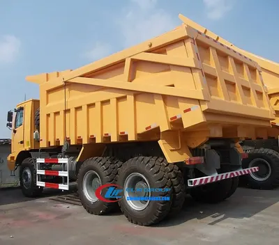 6×6 Sinotruk HOWO 70 ton off road dump truck in mining environment with side-tilt body loaded with gravel