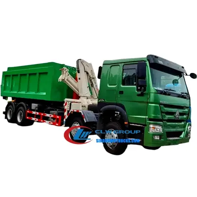 8×4 Sinotruk HOWO 25-ton hook lift dump truck with crane in gray cab, lifting a standard waste container