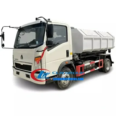 Side view of the HOWO 5m3 hook loader with open hopper and roller system in operation