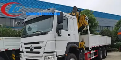 Rear view of the HOWO crane truck with boom extended and crane operator at the top seat