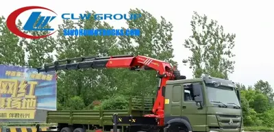 Sinotruk HOWO 18 ton knuckle boom crane in action at a construction site with boom extended and load suspended