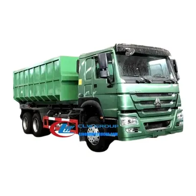 Side view of the HOWO garbage truck with container being lifted by the hook loader