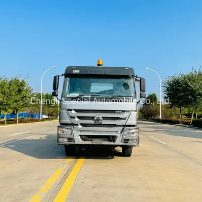 Side view of the HOWO garbage truck with the container lifted and the hook mechanism in operation
