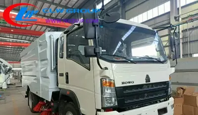 Sinotruk HOWO 7cbm road cleaning truck in urban setting with front brush and water spray bar active