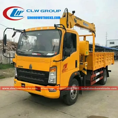 Sinotruk HOWO small boom truck with crane mounted on the rear, standing on a construction site in Ghana